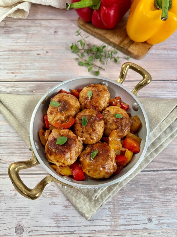 Serviamo le polpette ben calde accompagnate dai peperoni e guarnite con foglioline di maggiorana.